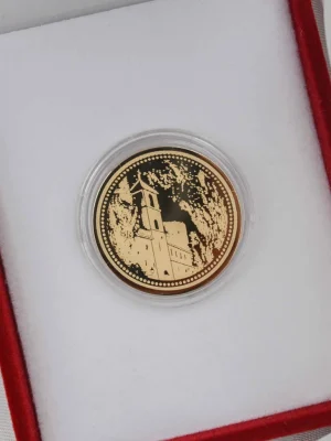 Zlatni zlatnik sa detaljnim prikazom manastira Ostrog, urezanog u steni planine. Novčić je smešten u crvenu kutiju sa belom postavom. Savršen poklon vere, zaštite i duhovnog značaja.