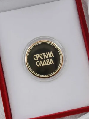 Zlatnik sa natpisom „Срећна Слава“, u elegantnoj crnoj pozadini sa zlatnim detaljima, postavljen u crvenu kutiju sa belom postavom. Idealan poklon za domaćina, vernika ili za čestitanje slave uz stil i simboliku.