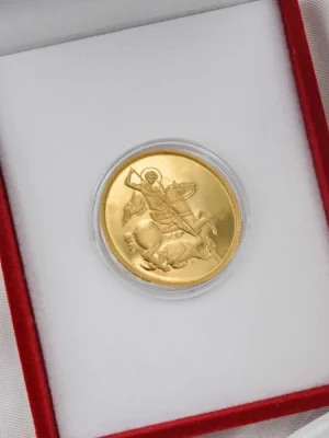 Dukatski zlatnik sa prikazom Svetog Georgija u borbi sa aždajom, klasičan hrišćanski simbol pobede dobra nad zlom. Smešten u crvenu kutiju sa belom postavom. Idealan poklon za Đurđevdan, vernike i kolekcionare