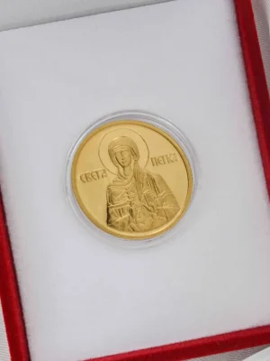Zlatni zlatnik sa likom Svete Petke, jedne od najvoljenijih pravoslavnih svetiteljki, poznate kao zaštitnica žena, porodice i zdravlja. Smešten u crvenu kutiju sa belom postavom – duhovni poklon sa velikim simboličkim značajem.